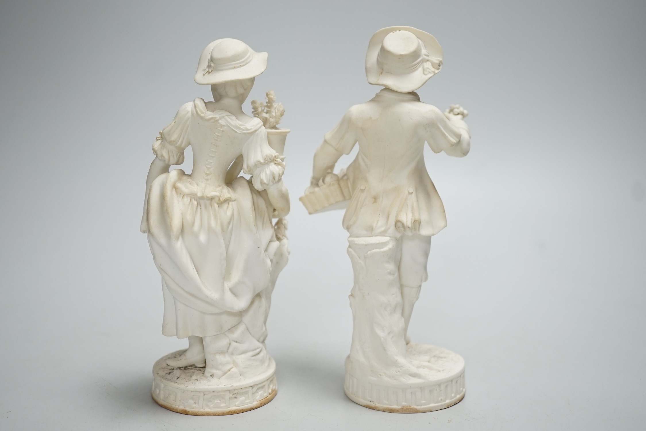 A pair of Minton biscuit figures of a boy and girl with flowers, on circular bases, 19cm